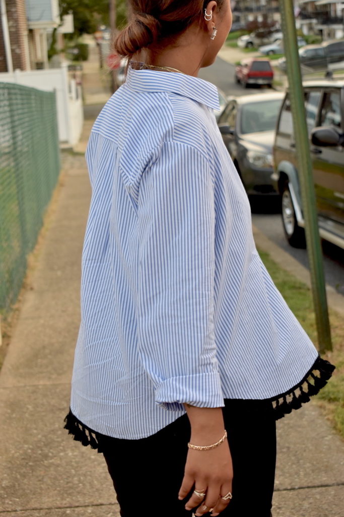 Female wearing a blue and white pinstripe tassel trim blouse displaying movement.