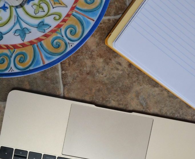 Macbook computer next to a writing pad and dish