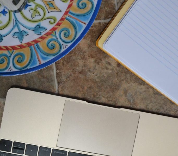 Macbook computer next to a writing pad and dish