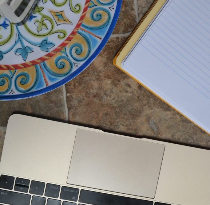 Macbook computer next to a writing pad and dish